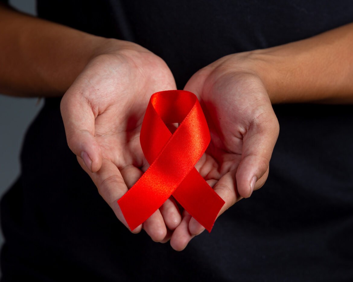 woman-hand-holding-red-ribbon-hiv-awareness-concept-world-aids-day-world-sexual-health-day